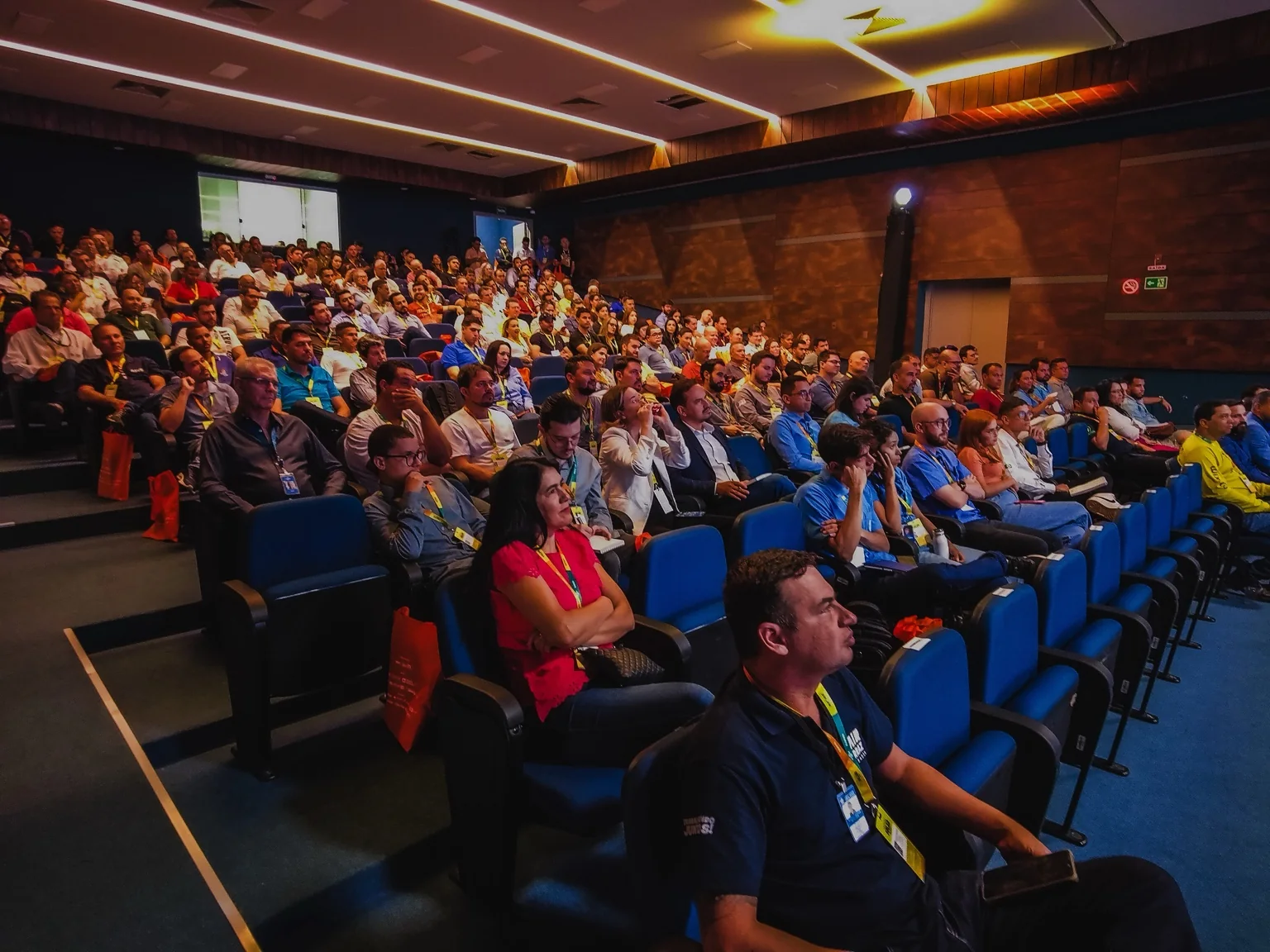 Grande auditório com profissionais reunidos durante evento empresarial.
